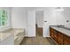 Bathroom featuring a soaking tub near a window, wood-look flooring, and a vanity with granite countertop at 3899 Leach Rd, Snellville, GA 30039