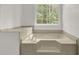 Close up of beige soaking tub, with neutral tile surround and window view to green foliage at 3899 Leach Rd, Snellville, GA 30039