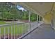 Long covered front porch with white railing, wood floor, painted yellow siding, and landscaped front yard at 3899 Leach Rd, Snellville, GA 30039