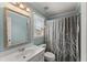 Bathroom with white vanity, toilet, window, and a shower with a gray patterned shower curtain at 3295 Millwood Se Trl, Smyrna, GA 30080