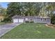 Ranch-style home with two-car garage, green door, and large front lawn with mature trees at 4983 Needle Knob Ct, Lithonia, GA 30038