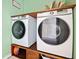 Convenient laundry room with modern washer and dryer units on a custom wood shelf at 5780 Winding Lakes Dr, Cumming, GA 30028
