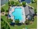 Aerial view of a sparkling community pool with ample seating, a nearby firepit, and lush green landscaping at 5780 Winding Lakes Dr, Cumming, GA 30028