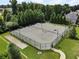 Aerial view of fenced tennis courts with lighting, surrounded by trees and green space at 5780 Winding Lakes Dr, Cumming, GA 30028