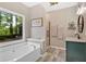 This elegant main bathroom features a soaking tub, glass enclosed shower and a serene view of the outdoors at 17 Brightwater Cv, Dallas, GA 30157