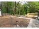 View of the backyard with a dirt lot and a new wooden deck to the white brick home at 6881 Homestead Rd, Rex, GA 30273