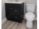 Well-lit bathroom showcasing a dark vanity, toilet, and wood-look flooring at 6881 Homestead Rd, Rex, GA 30273