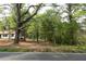 Exterior ground-level view of home and surrounding large wooded lot near a paved road at 6881 Homestead Rd, Rex, GA 30273