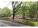 Exterior shot of the white home with a black roof surrounded by green trees and a long yard at 6881 Homestead Rd, Rex, GA 30273