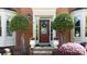 Close-up of an inviting front door with decorative wreath, flanked by manicured trees and planters at 5405 Preserve Cir, Johns Creek, GA 30005
