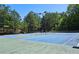 Outdoor tennis courts with blue playing surface, surrounded by tall trees and lighting fixtures at 542 Simonton Ridge Trl, Lawrenceville, GA 30045