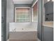 Bathroom showcasing a built-in tub with tile surround and a window with wood blinds at 2023 Reserve Pkwy, Mcdonough, GA 30253
