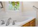 Close up of a bathroom soaking tub with decorative stained glass window at 1213 Blue Springs Dr, Loganville, GA 30052