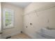 Well-lit laundry room with utility sink, storage shelf, and tiled floor at 1213 Blue Springs Dr, Loganville, GA 30052
