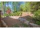 Grassy area held in by a stone retaining wall surrounded by a tree lined perimeter at 2566 Garrison Sw, Marietta, GA 30064
