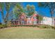 Charming two-story brick home with black shutters, a manicured lawn, mature trees, and colorful flower beds at 2566 Garrison Sw, Marietta, GA 30064