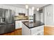 Well-lit kitchen featuring a stainless steel fridge, kitchen island with granite countertop, and white cabinetry at 4415 Dorset Ln, Suwanee, GA 30024