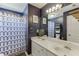 Stylish bathroom with navy walls, double vanity with modern fixtures, and shower with blue patterned curtain at 5093 Heartland Trl, Hoschton, GA 30548