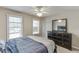 Well-lit bedroom featuring a ceiling fan, and windows offering natural light, and a black dresser with mirror at 5093 Heartland Trl, Hoschton, GA 30548