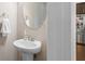 Stylish half bathroom with pedestal sink and oval mirror adjacent to the open kitchen area at 1536 Drew Nw Dr, Atlanta, GA 30318