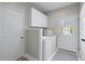 Bright laundry room with washer, dryer, white cabinets, folding counter and access to exterior at 605 Tatum Ct, Alpharetta, GA 30022