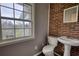 Half-bathroom with pedestal sink, toilet, and brick accent wall at 1277 Bethany Rd, Covington, GA 30016