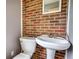 Close-up of a half-bathroom with pedestal sink, toilet, and brick accent wall at 1277 Bethany Rd, Covington, GA 30016