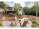 Backyard featuring a stone patio with chairs, overlooking the house with a deck, surrounded by trees and greenery at 1295 Lindenwood Ne Ln, Brookhaven, GA 30319