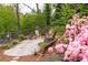 Landscaped backyard patio area with seating and a fire pit, surrounded by lush greenery and vibrant pink flowers at 1295 Lindenwood Ne Ln, Brookhaven, GA 30319
