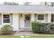Close-up of a freshly painted gray front door with a wreath, flanked by green bushes and white brick at 1295 Lindenwood Ne Ln, Brookhaven, GA 30319