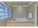 Bathroom with a jetted tub, tile surround, and natural light at 6273 Clapham Ln, Johns Creek, GA 30097