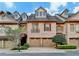 Beautiful brick townhome featuring an attached two-car garage and manicured landscaping for curb appeal at 6273 Clapham Ln, Johns Creek, GA 30097