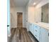 Bathroom featuring white cabinets, a large mirror, and plank flooring at 586 Rodeo Dr, Auburn, GA 30102