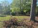 Exterior view of home from a distance with trees in the foreground, set on a spacious, greenery filled lot at 1099 Warren Dr, Riverdale, GA 30296