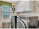 Well-lit laundry room with side by side washer and dryer, white cabinets and a window at 1705 Butler Bridge Rd, Covington, GA 30016