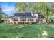 Back exterior view of home with sunroom, brick foundation, and large grassy yard at 495 Buttercup Trl, Lawrenceville, GA 30046
