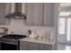 Updated kitchen shows gray cabinets, modern range hood and gas range, gold hardware and backsplash at 1179 Bennett Creek Overlook, Suwanee, GA 30024