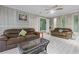 Cozy living room featuring two brown sofas, a ceiling fan, and sleek white wood-look floors at 2520 Hartford Dr, Ellenwood, GA 30294
