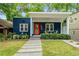 Charming blue bungalow with vibrant orange door and inviting covered front porch and landscaped front yard at 830 Belgrade Ne Ave, Atlanta, GA 30306