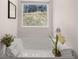 Bright bathtub with a view of nature outside the window, and floral decorations at 1344 Riverstone Rd # 108, Jonesboro, GA 30238