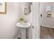 Bright powder room featuring a pedestal sink, round mirror, and wood-look flooring and window allowing natural light at 1346 Riverstone Rd # 107, Jonesboro, GA 30238