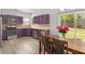 Eat-in kitchen with purple cabinetry, stainless steel appliances, granite countertops, and backyard views at 395 Anvil Way, Austell, GA 30168