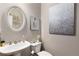 Stylish half bathroom with white pedestal sink, toilet, decorative mirror, and modern art pieces at 895 Ovalene Sw Ln, Marietta, GA 30064