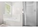 Tiled bathroom featuring tub and shower with glass door and bright window, inviting relaxation at 782 Ridgeland Trl, Clarkston, GA 30021