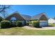Beautiful brick home featuring an attached garage, well-manicured shrubs, and front yard bench at 116 Ridge Xing, Temple, GA 30179
