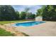 In-ground pool surrounded by a large concrete patio, lush trees and a storage shed at 116 Ridge Xing, Temple, GA 30179