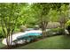 A backyard pool is surrounded by lush greenery and trees, and includes a lounge seating area at 7000 Hunters Knl, Atlanta, GA 30328
