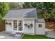 Backyard outbuilding with double French doors, hanging flowers, and an attached storage shed at 3601 Cedar Springs Ln, Loganville, GA 30052