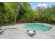 Community pool with lounge chairs, tables, and a hot tub surrounded by lush trees at 3601 Cedar Springs Ln, Loganville, GA 30052
