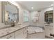 Luxurious bathroom with marble countertops, soaking tub, decorative mirrors, and a glass-enclosed shower at 568 Timberland Dr, Atlanta, GA 30342